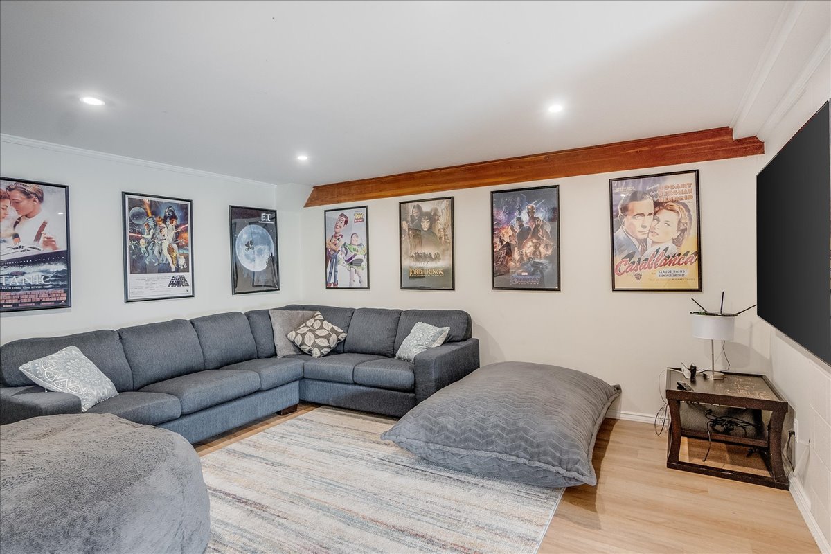 Downstairs movie theatre with sectional sofa, framed film posters, and 70-inch TV