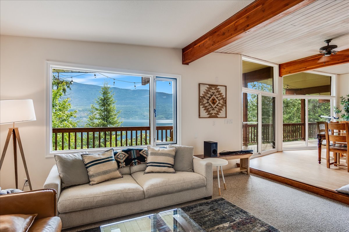 Living room at Kootenay Getaway with floor-to-ceiling windows looking out to Kootenay Lake and the mountains beyond